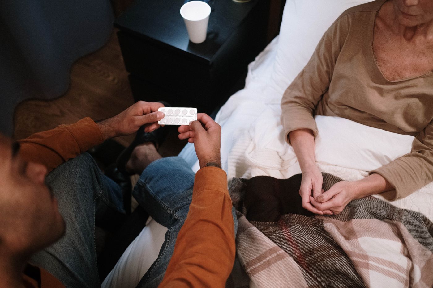 A caregiver sitting with a senior at the bedside